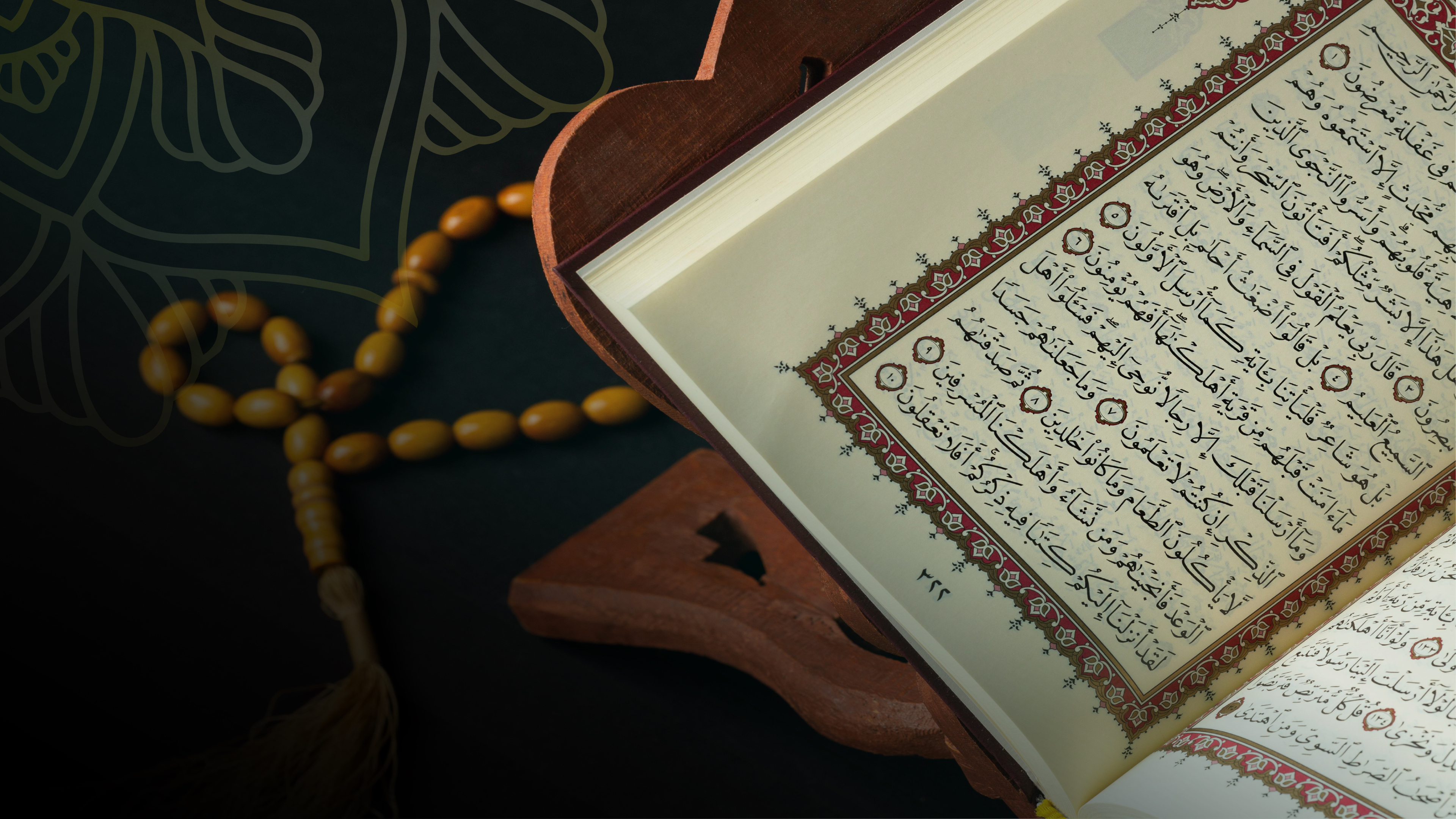 An open muṣḥaf on a carved wooden rehl, with amber prayer beads resting beside it